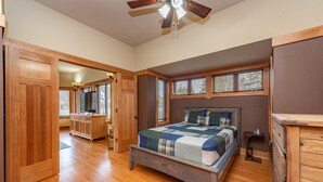 Une chambre avec un lit en bois, un ventilateur de plafond et une fenêtre avec des stores.