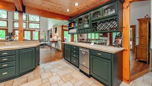 A spacious kitchen with green cabinets, a built-in dishwasher, and a large island.