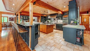 A spacious kitchen with wooden beams, a central island, and bar stools.