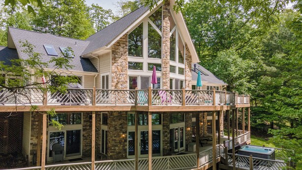 A two-story house with a balcony, large windows, and a hot tub.