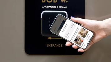 A digital device displaying a hotel check-in interface with a smartphone held in a hand.