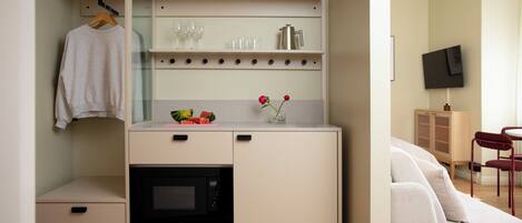 A compact kitchenette with a microwave, a small oven, and a countertop with a vase of flowers.