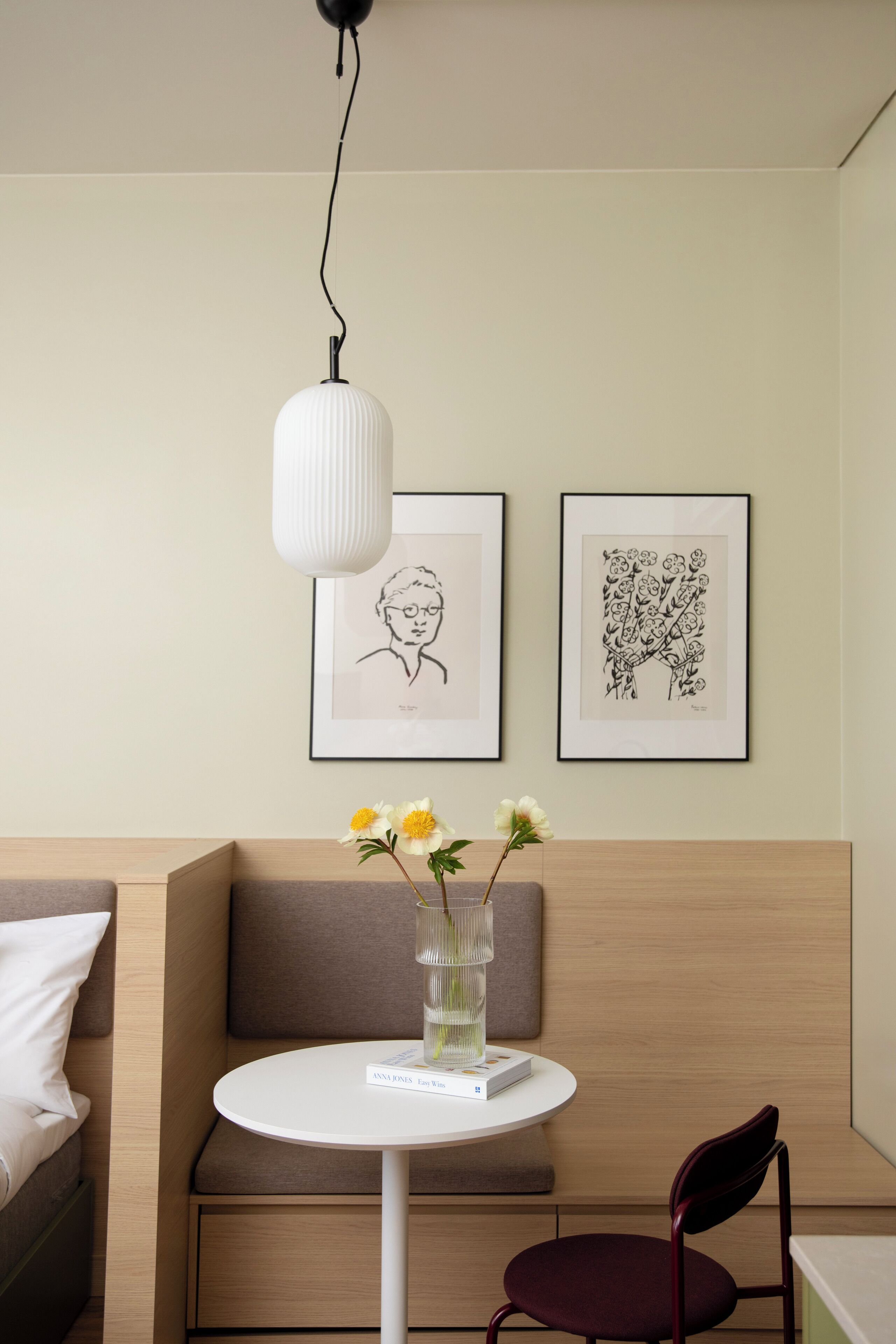 Een moderne kamer met een ronde tafel, een stoel, een bank en twee kunstwerken in lijsten aan de muur.