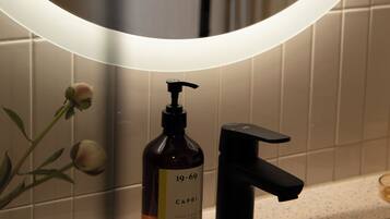 A bathroom with a mirror, a hand soap dispenser, and a faucet.