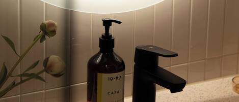 A bathroom with a mirror, a hand soap dispenser, and a faucet.