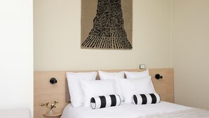 A neatly made bed with white bedding and black and white striped pillows, a wooden headboard, and a wall-mounted clock. - Bob W Turku City Centre (Turku)
