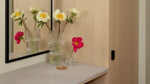 A bathroom vanity with a mirror, a light-colored countertop, and three glass vases with flowers. - Bob W Turku City Centre (Turku)