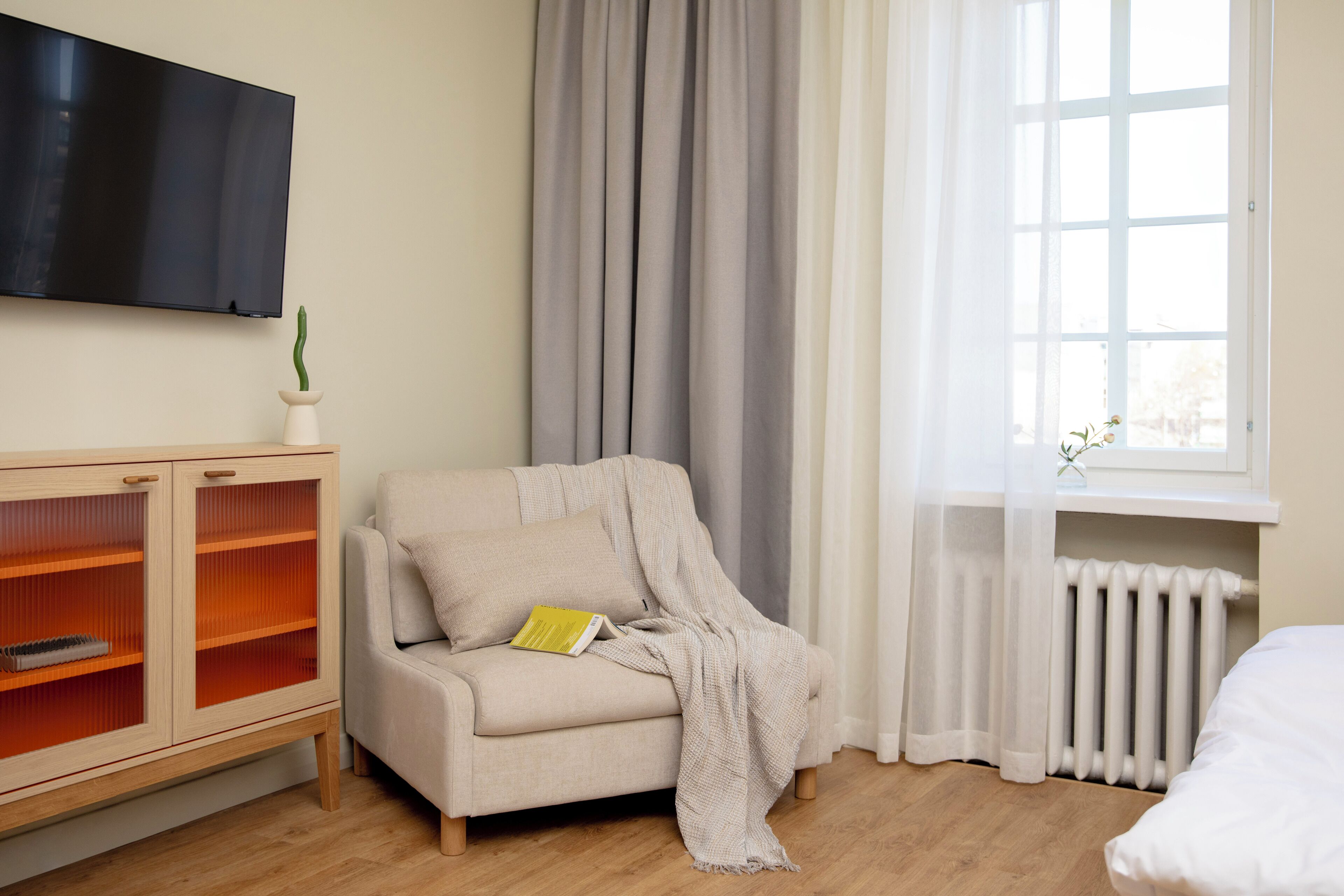 Habitación con sofá, armario de vidrio, radiador y ventana con cortinas.