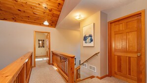 A wooden staircase with a handrail, carpeted steps, a wooden door, and a framed picture on the wall.