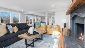 Un salon moderne avec un canapé, des fauteuils, une table basse et une cheminée.
