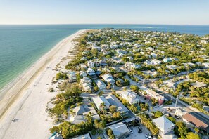 An aerial view of a coastal residential area with houses, a beach, and a clear view of the ocean. - Barefoot Mermaid 1, great Ami location steps to the beach/fun on Pine Ave (Anna Maria)