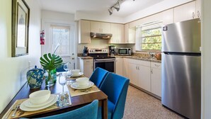 A compact kitchen with light wood cabinets, a stainless steel refrigerator, a microwave, and an oven.