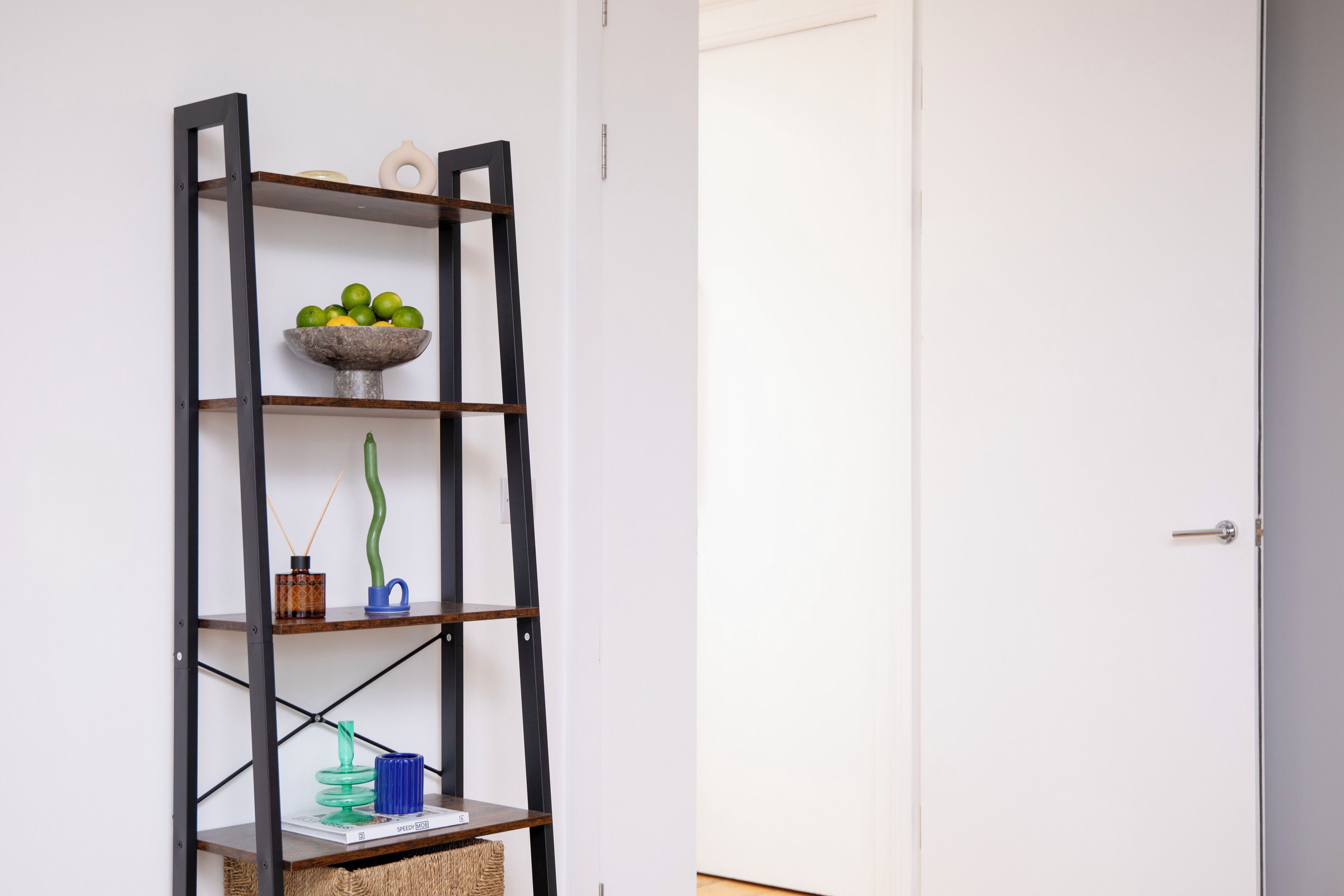 A tall, black metal shelving unit with various decorative items on each shelf.