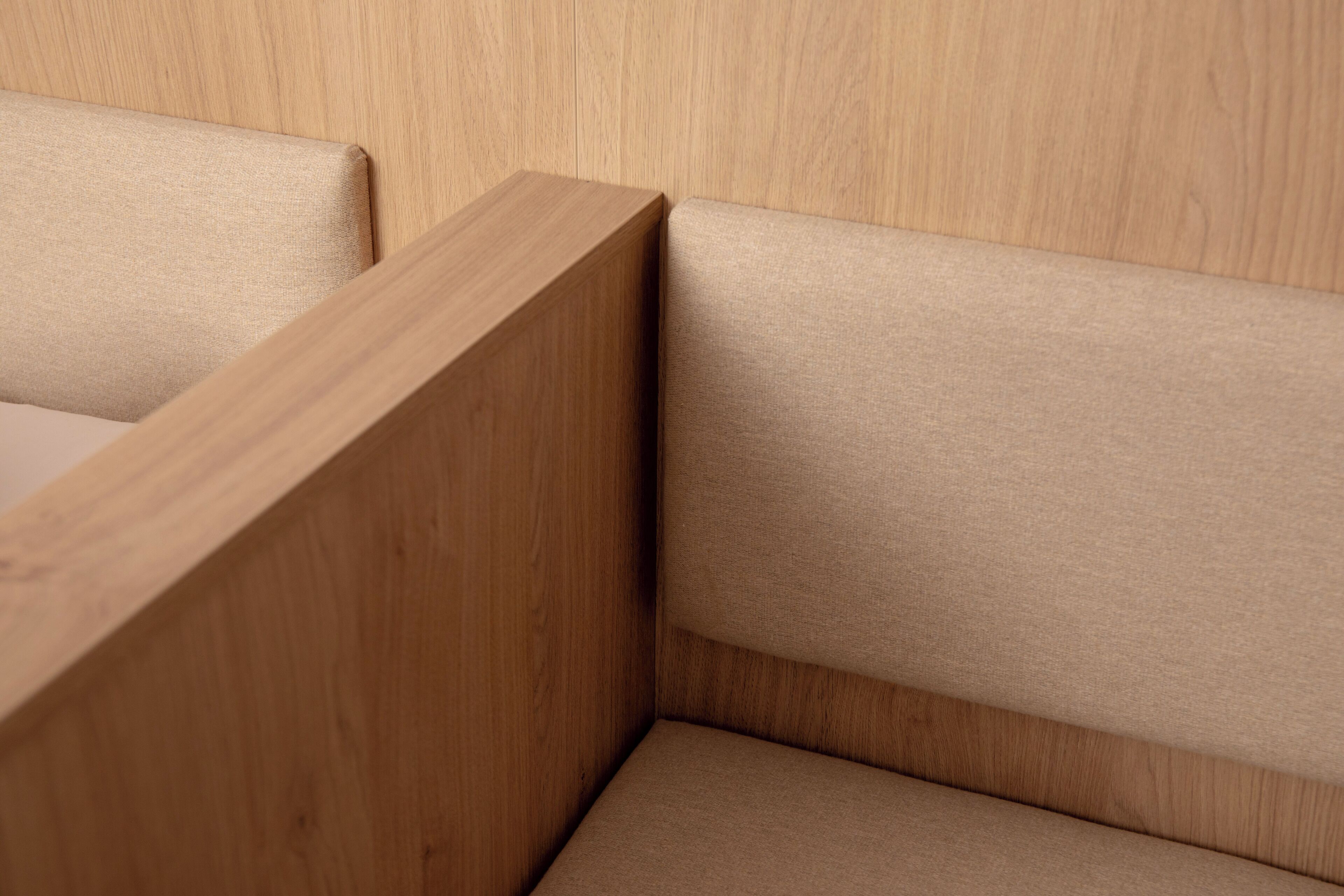 A corner of a room with a wooden headboard and a beige upholstered headboard.