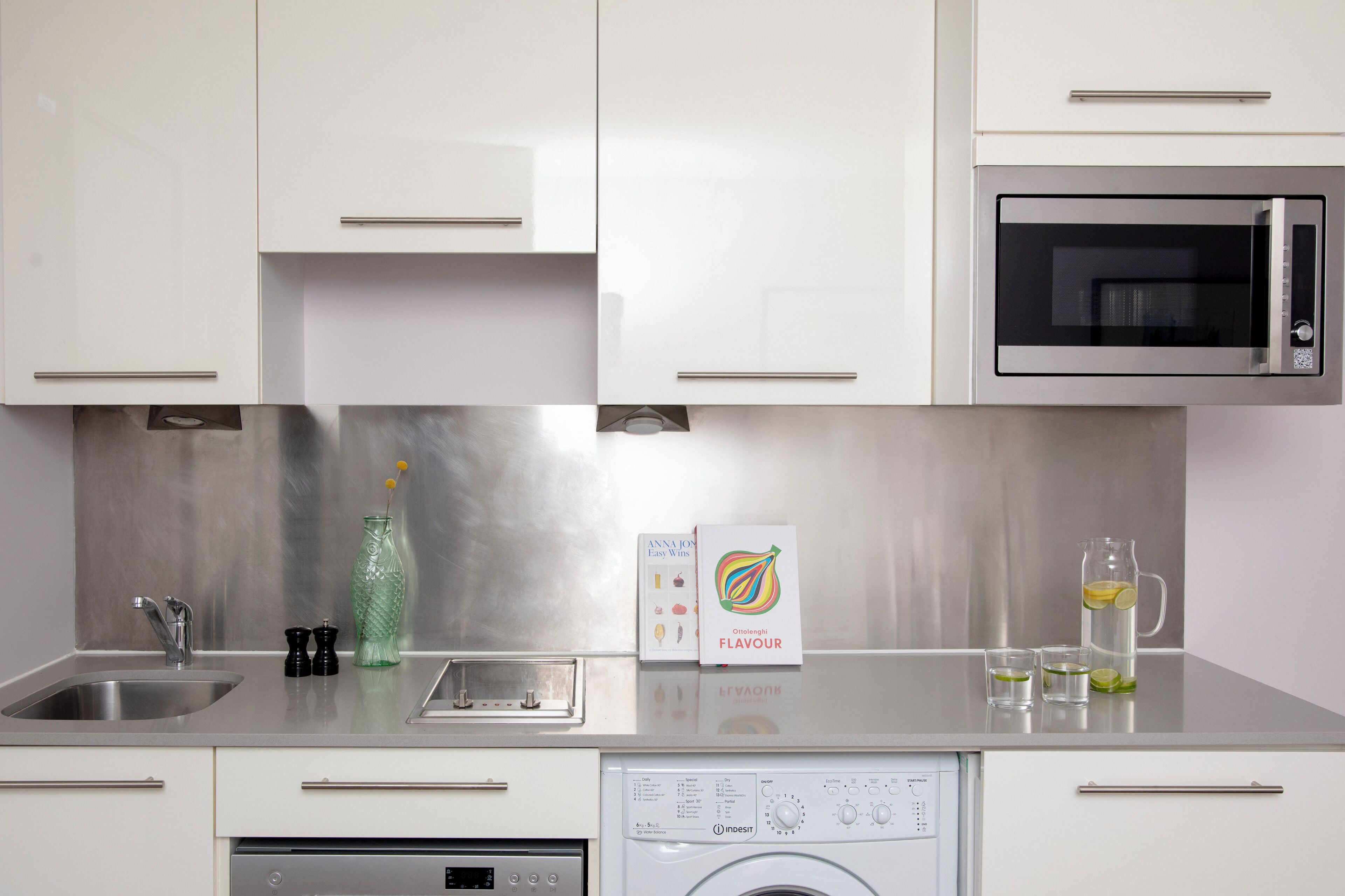 Une cuisine moderne équipée d’appareils électroménagers en acier inoxydable, d’un lave-vaisselle et d’une machine à laver.