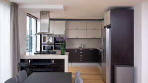 A modern kitchen with a central island, built-in appliances, and a dining area with a table and chairs. - Bob W London Tower Hill  - Residences (London)