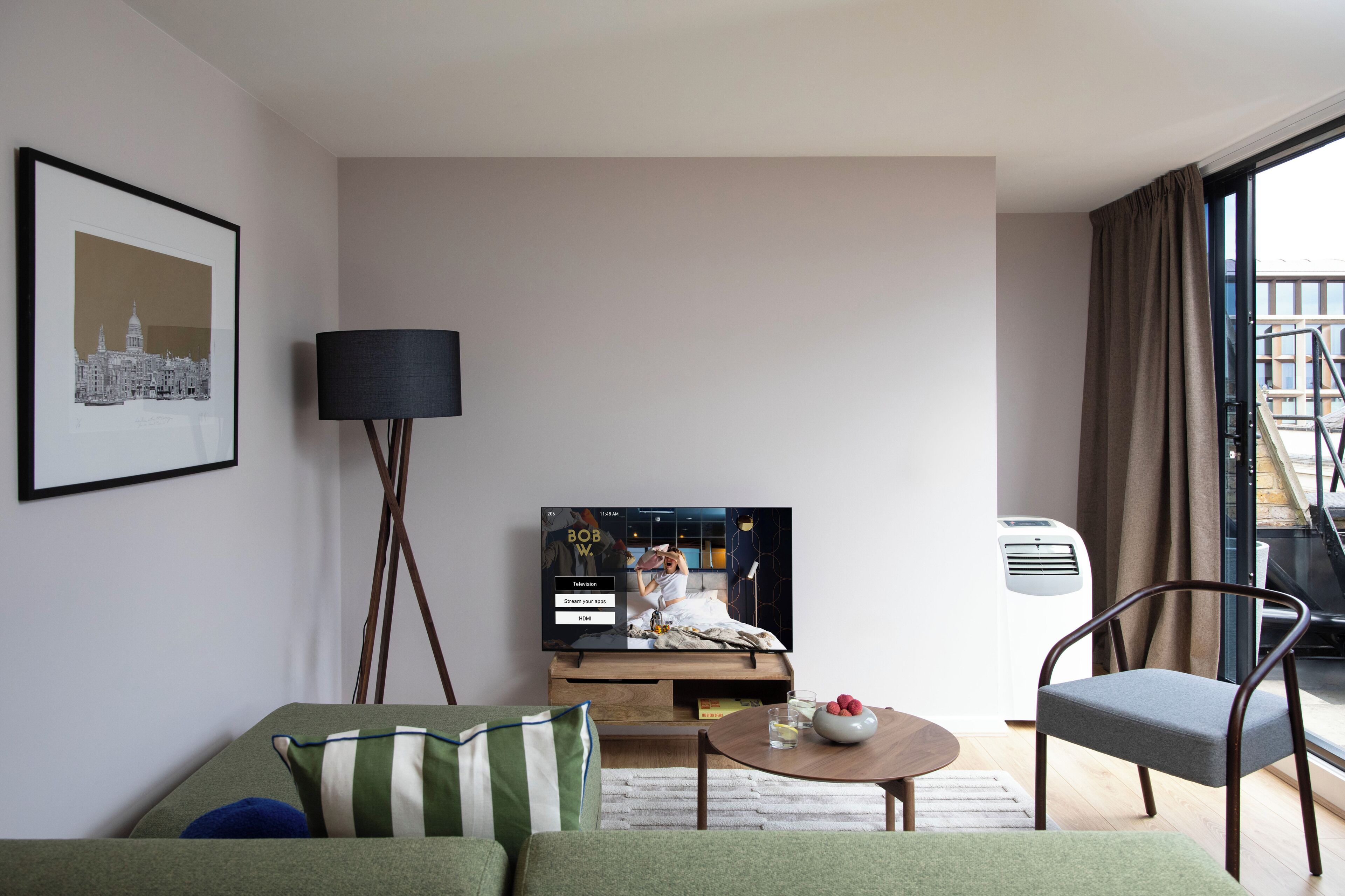 Una sala de estar moderna con una televisión de pantalla plana, un sofá, una mesa de centro y un sillón.