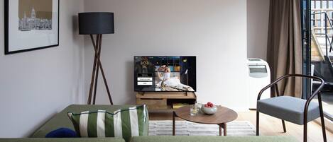Moderni olohuone, jossa on litteänäyttöinen televisio, sohva, sohvapöytä ja nojatuoli.