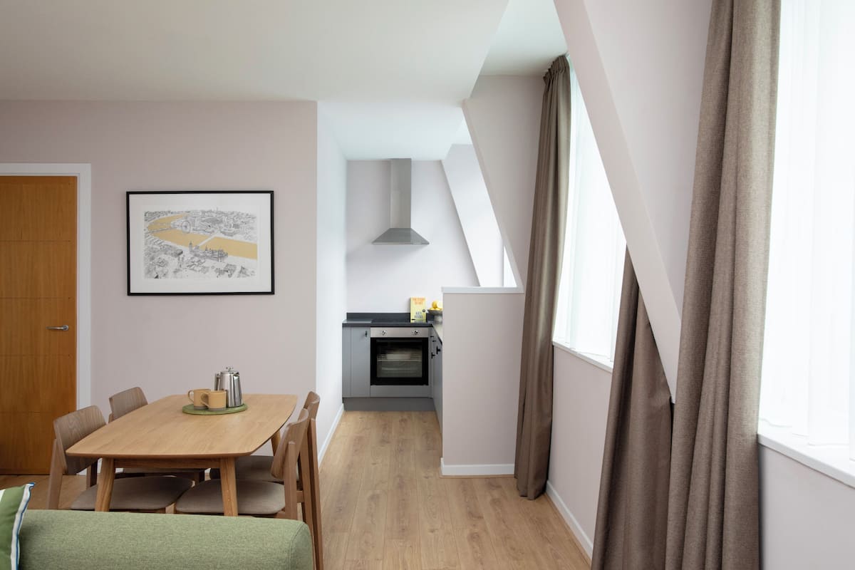 A modern kitchen with a built-in oven and a dining area with a wooden table and chairs.