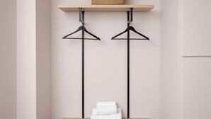 A minimalist room with a wooden shelf, two black hangers, and a stack of white towels on a green cabinet. - Bob W London St. Paul's (London)