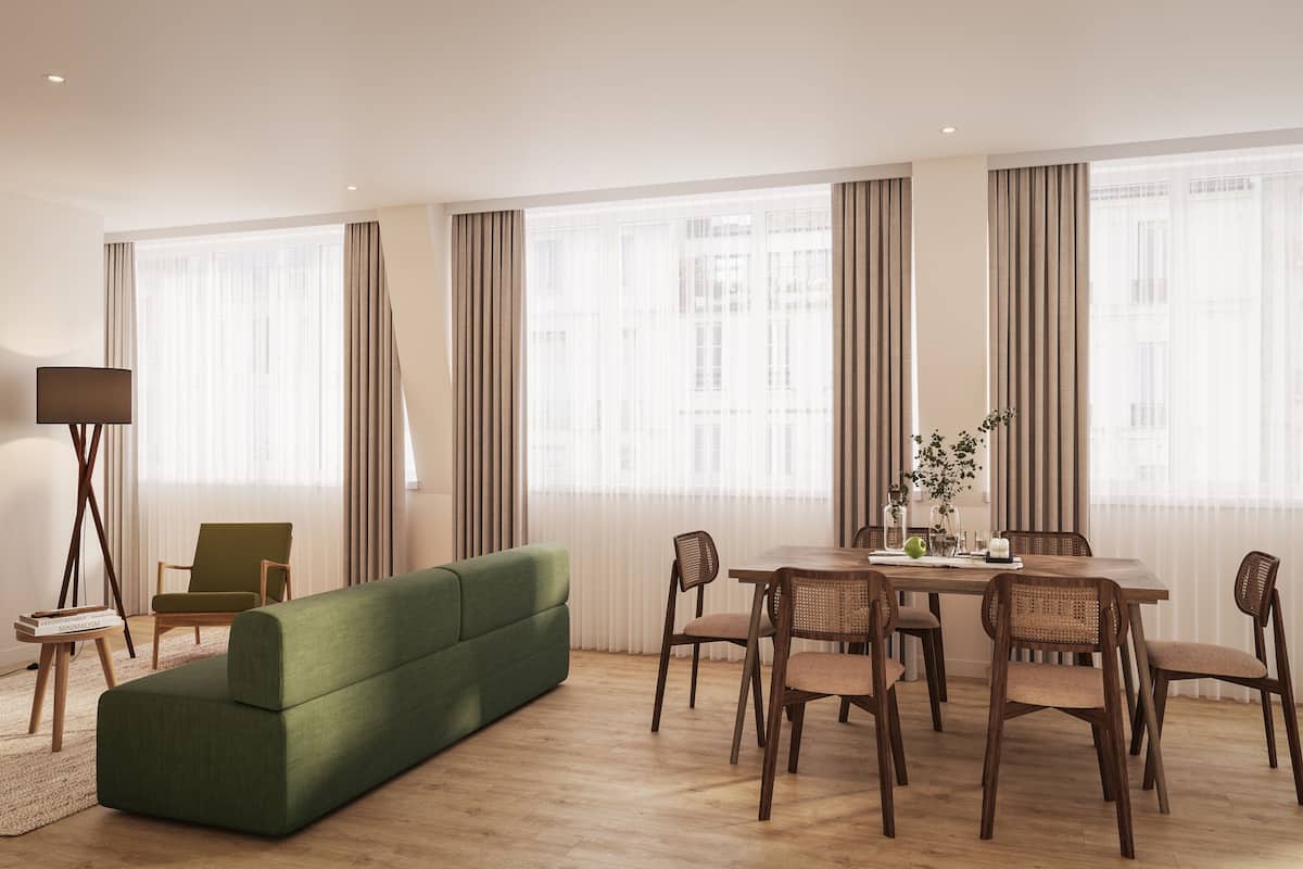 A modern living room with a green sofa, wooden dining table, and chairs.