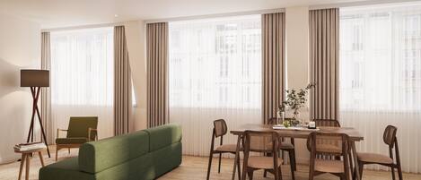 A modern living room with a green sofa, wooden dining table, and chairs.