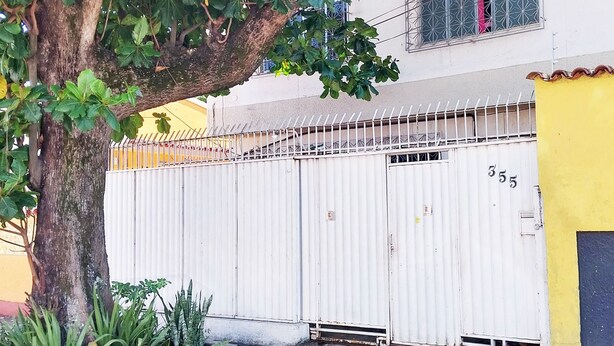 Un espace clos, avec un arbre et un bâtiment en arrière-plan.