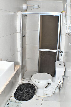 Ein kleines Badezimmer mit Duschkabine, Toilette und Waschbecken.