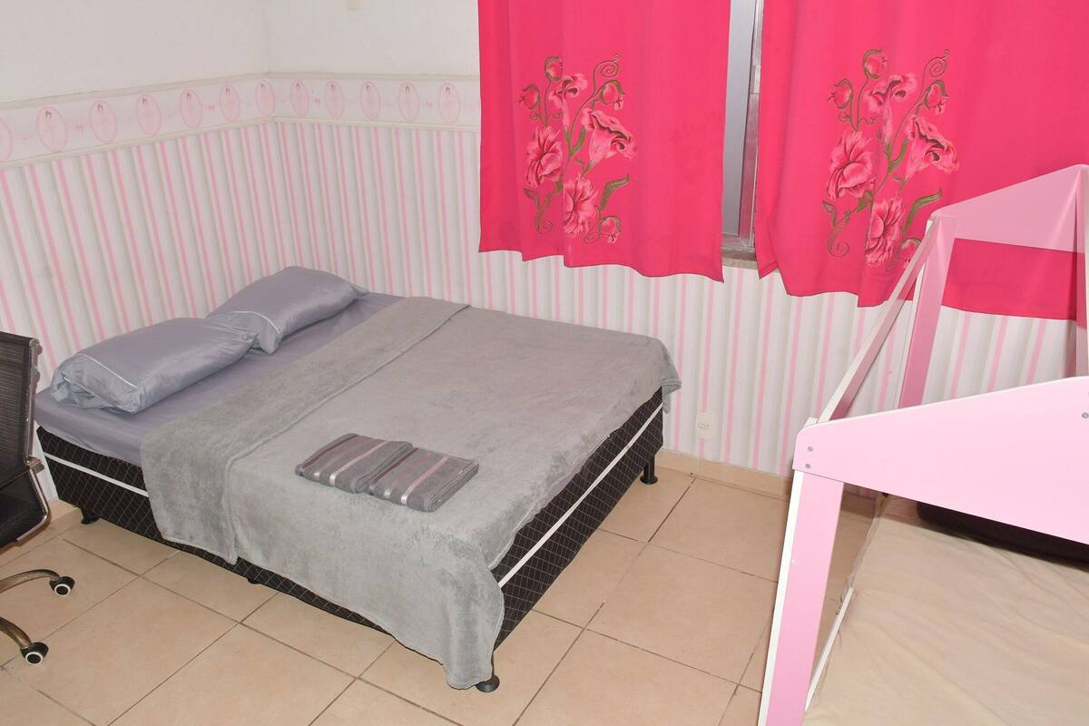 A bedroom with a bed, a desk, and a chair.