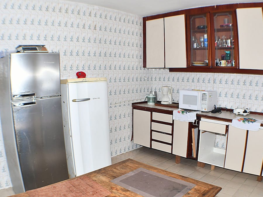 A kitchen with a refrigerator, microwave, and wooden cabinets.