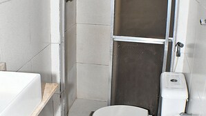 Une salle de bain compacte comprenant un espace douche, des toilettes et un lavabo.