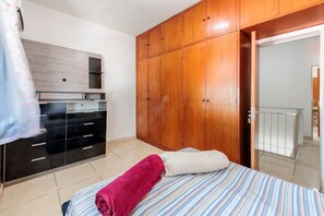 Ein Schlafzimmer mit einem Bett, einem Holzschrank und einer Tür, die auf einen Balkon führt.