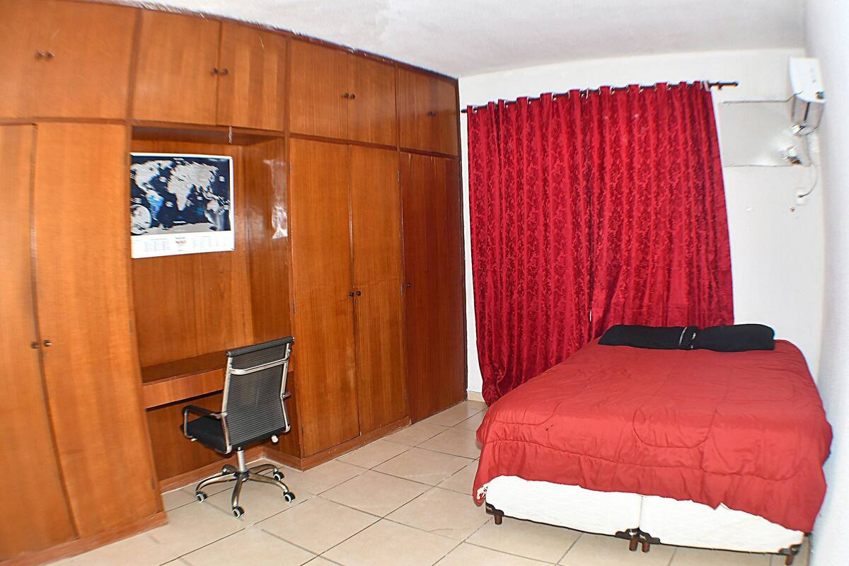 A bedroom with a bed, a desk, and a wardrobe.
