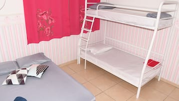 Una cama litera con escalera, una cama individual con almohadas y un papel tapiz a rayas.