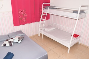 Een stapelbed met een ladder, een eenpersoonsbed met kussens, en behang met strepen.