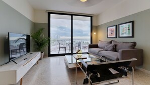 A modern living room with a large window, a sofa, a coffee table, and a TV. - La Moderna Downtown Nights by Wynwood (Panama City)