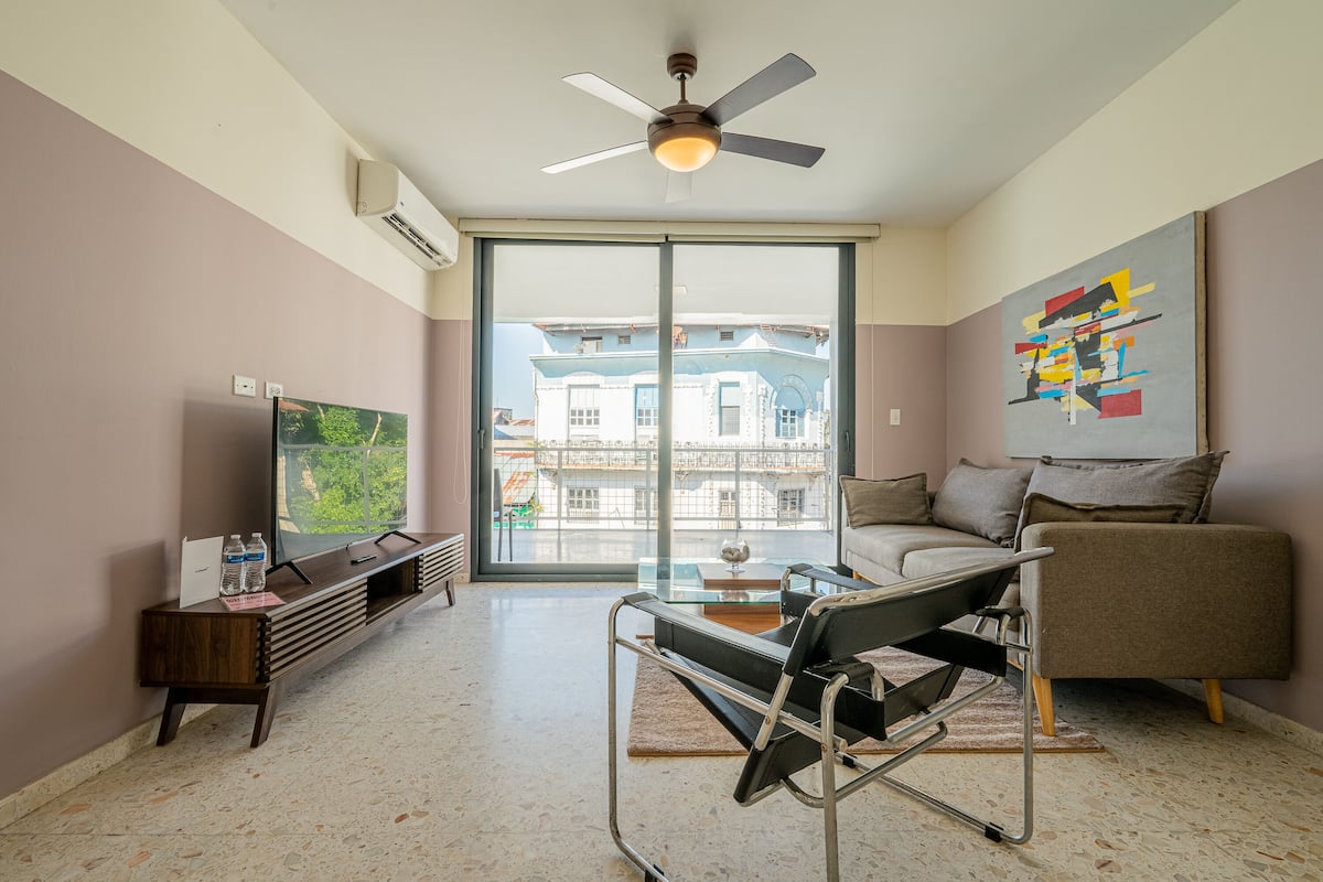 A modern living room with a sofa, a coffee table, a TV, and a ceiling fan.