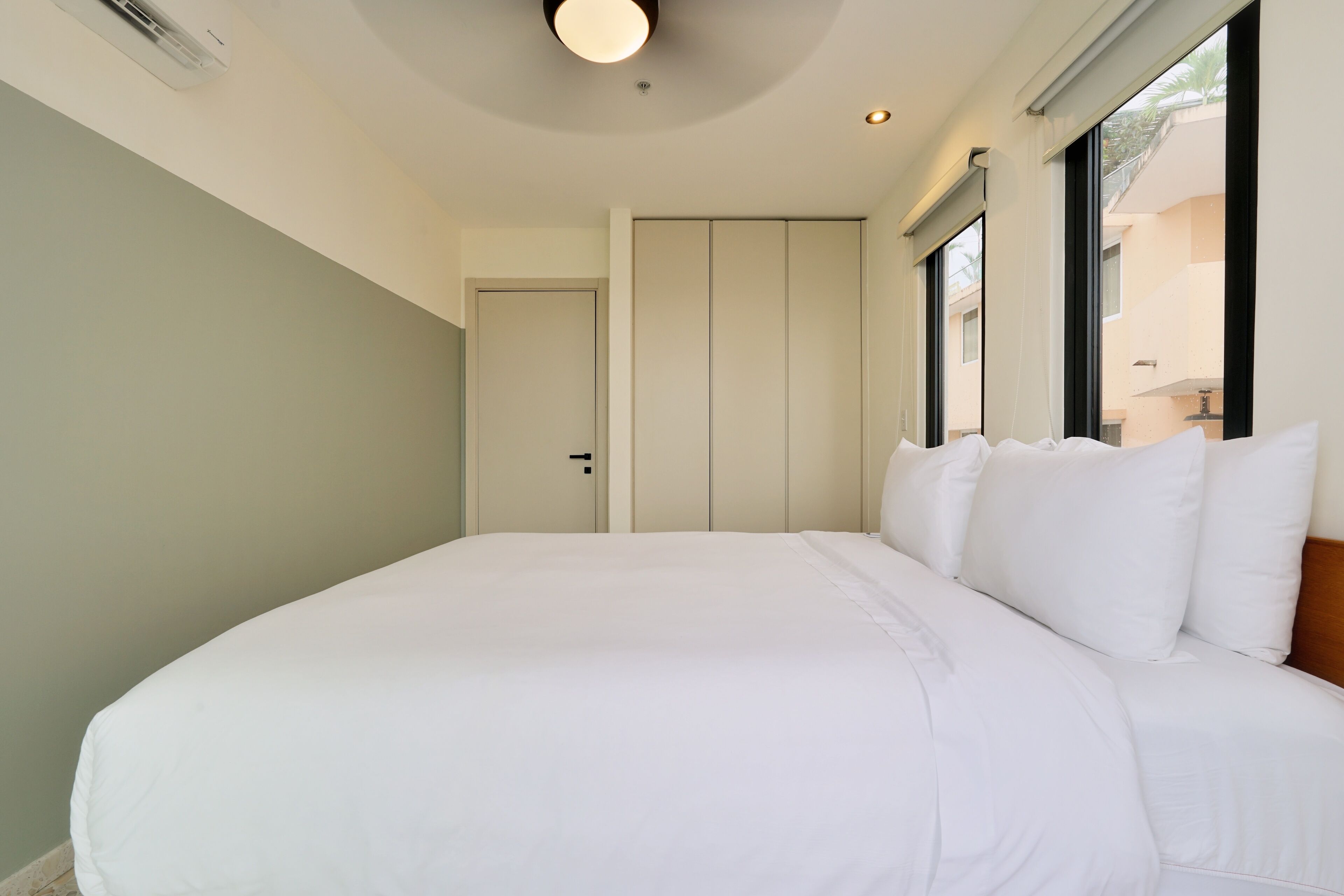 Un dormitorio con una cama grande, una puerta y una ventana.
