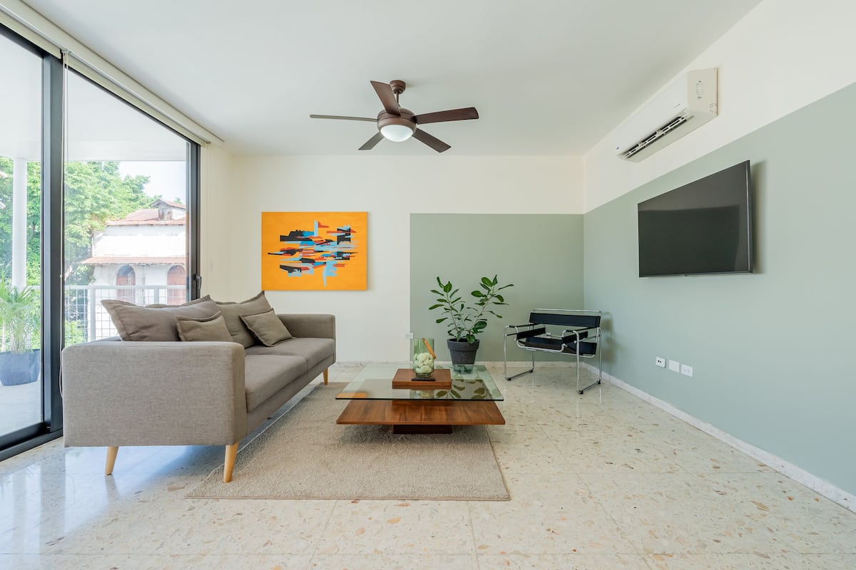 A modern living room with a sofa, coffee table, and artwork on the wall.