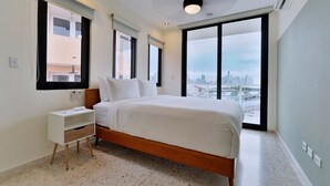A modern hotel room with a large bed, a nightstand, a city view, and a ceiling light. - La Moderna Downtown Nights by Wynwood (Panama City)