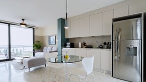 A modern kitchen with a glass dining table, white chairs, and a stainless steel refrigerator. - La Moderna Downtown Nights by Wynwood (Panama City)