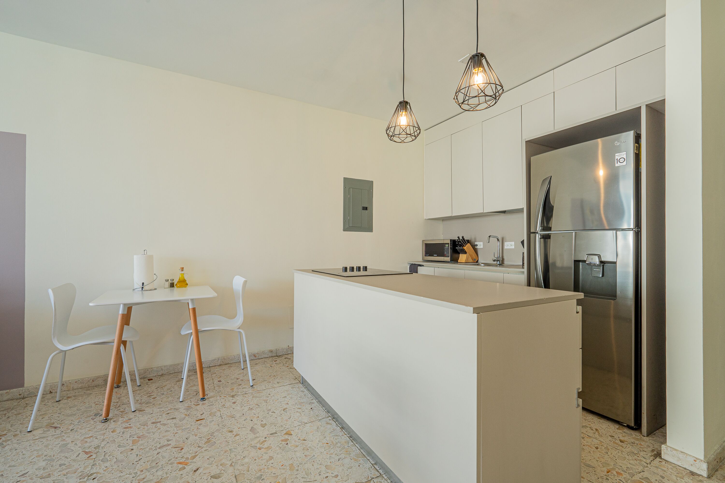 Eine moderne Küche mit einer zentralen Kochinsel, weißen Schränken und einem Edelstahl-Kühlschrank.