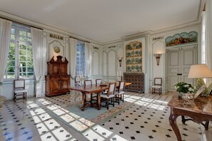 Une salle à manger avec une grande table en bois, des chaises, un buffet et un tapis à motifs.