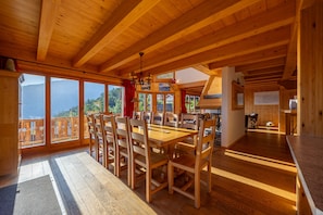 Un interior de madera con comedor, ventanas grandes y vistas al exterior.