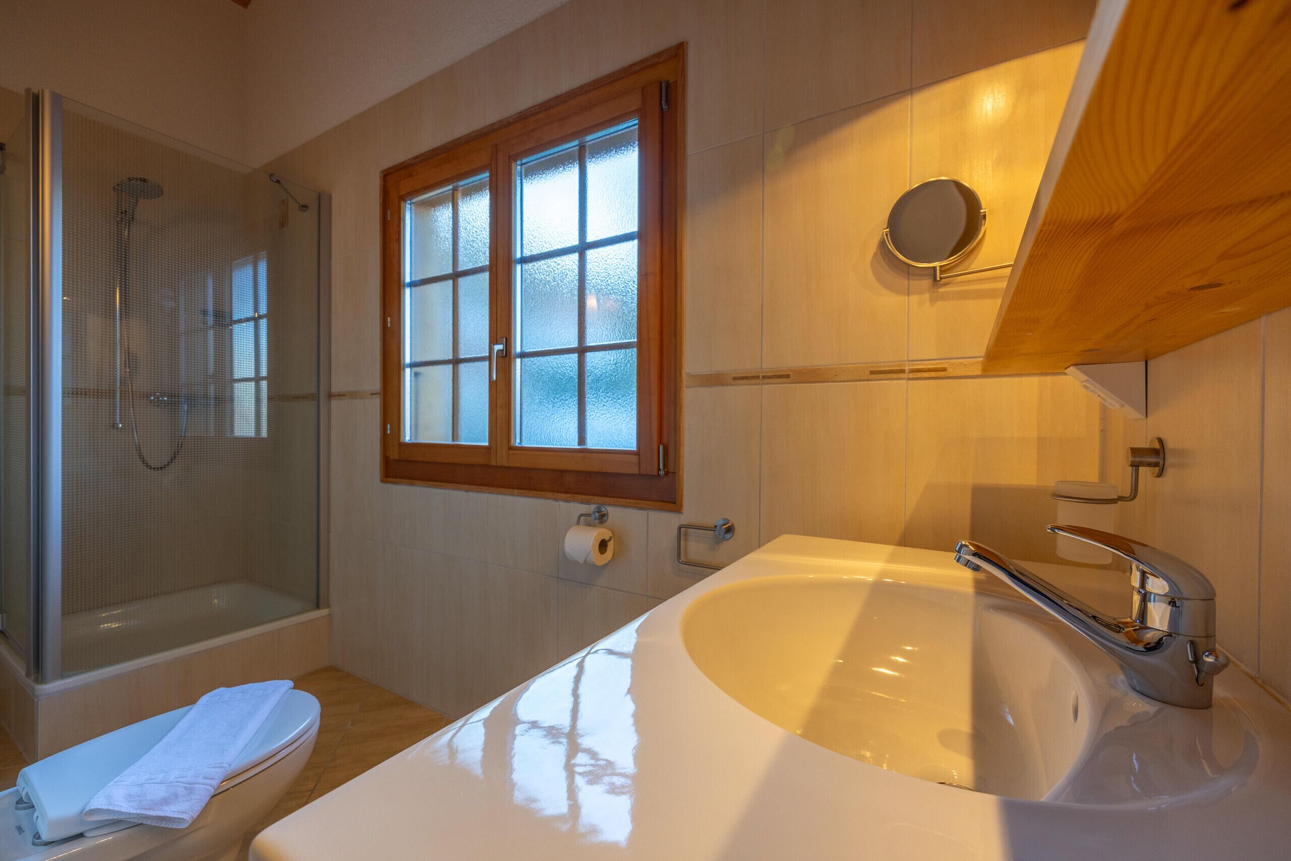 Un bagno con doccia vetro, vasca da bagno ampia, un lavabo con specchio e una finestra con vetro decorato.