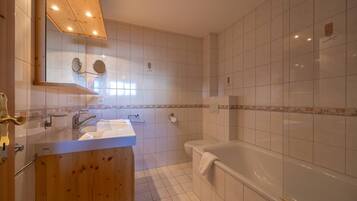A bathroom with a wooden vanity, a sink, a mirror, a toilet, and a bathtub.