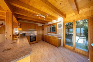 A modern kitchen with wooden cabinets, a granite countertop, and a large window. - Chalet Vansamis, views & sauna (Haute-Nendaz)