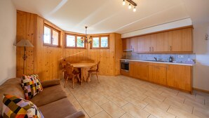 Zona d'estar acollidora amb un sofà, una taula de dinar i armaris de fusta.