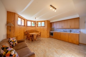 A cozy living area with a sofa, a dining table, and wooden cabinets. - Chalet Vansamis, views & sauna (Haute-Nendaz)