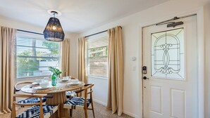 A dining area with a round table, chairs, and a hanging light fixture. - Barefoot Mermaid 4, steps to the beach (Anna Maria)